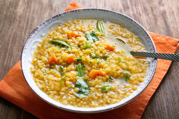 Plate with tasty lentil dish on wooden table, closeup