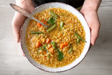 Young woman holding plate with tasty lentil dish, closeup