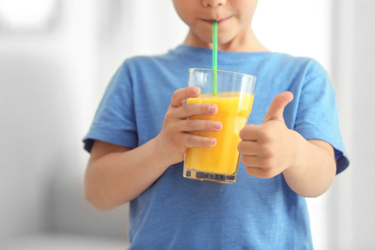Cute little boy drinking juice at home, closeup