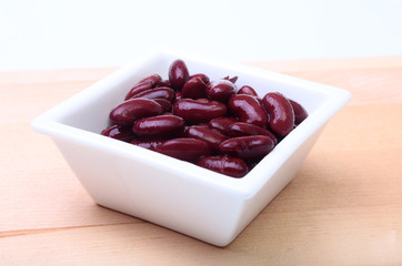 Heap of canned red kidney beans in the sauce in white bowl. vegetarian food. Phaseolus vulgaris.