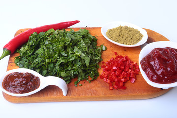Fresh green cilantro, coriander leaves, tomato paste, chili pepper and spices on a wooden board. Ingredients for meat sauce.