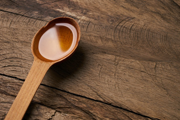 Wooden Spoon of cooking olive oil isolated on wooden background with copy space.