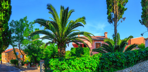 Fototapeta na wymiar Traditional european Mediterranean architectural style, streets & houses with terracotta roofs, surrounded by cypress, palm, olive, pine trees, on coast azure sea. Location of the prestigious estates