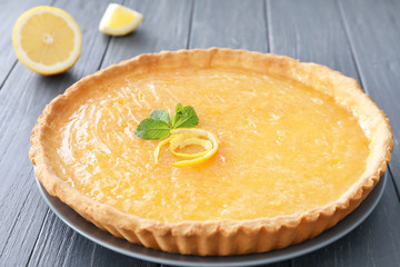 Delicious tart with sliced lemon on table