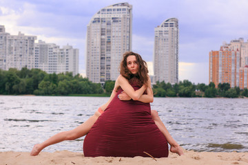 Cute curly girl sitting on an armchair bag at a beach in the city