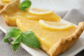 Pieces of tart decorated with mint and lemon slices on plate