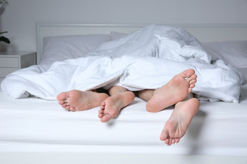 Feet of couple having sex under blanket at home