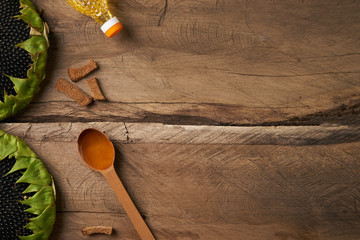 Sunflower and spoon with oil, bottle with a sunflower oil on wooden rustic table. Top view, copy space.