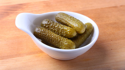 Bowl with pickled gherkins, cucumbers on wooden background close up. Pickles.