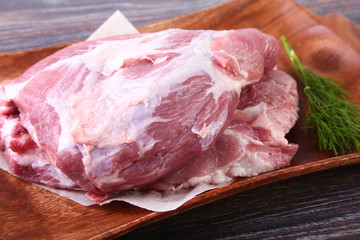 Raw pork steaks on wooden board with herbs, garlic and spices ready for cooking. Selective focus.