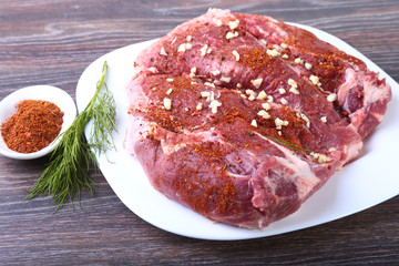 Raw pork steaks on wooden board with herbs, garlic and spices ready for cooking. Selective focus.