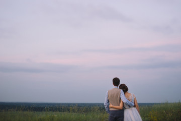 Romantic and happy caucasian couple in stylish clothes hugging on the background of beautiful nature. Love, relationships, romance, happiness concept. Man and woman walking outdoors together.