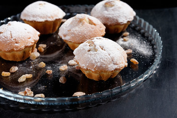 heap of cupcakes with raisins on glass plate, black background