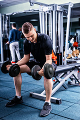 Handsome sportive man in sportswear lifting some weights