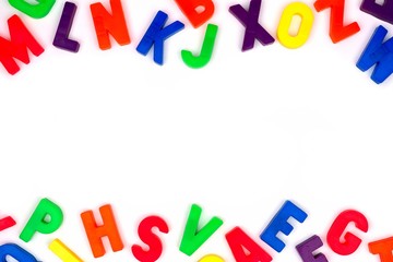 Double border of colorful toy magnetic alphabet letters over a white background