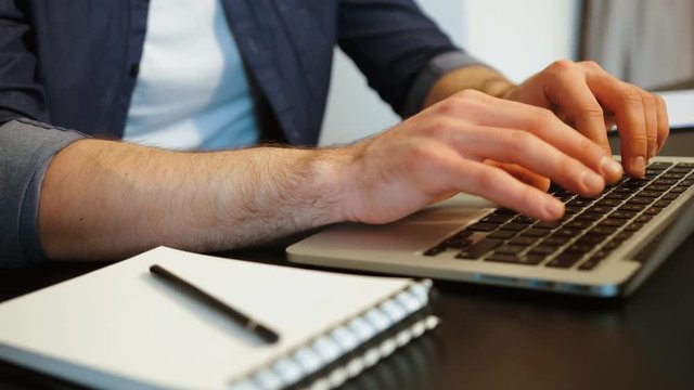 Portrait of hands of caucasian man at his work place in stylish modern office typing on laptop. Indoor.
