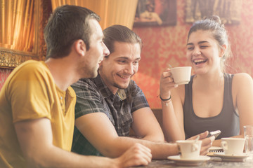 Group of friends in a coffee shop, discussing some content on their phone