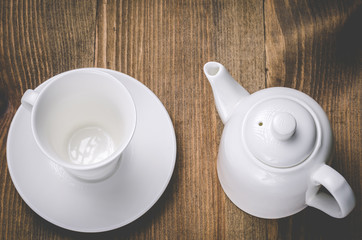 white teapot and empty cup on a wooden background/white teapot and empty cup on a wooden background. Top view