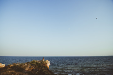 влюблённая пара стоящая на мысе в обнимку на фоне моря