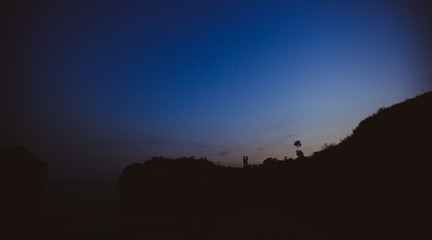 влюблённая пара стоящая в обнимку на фоне  закатного неба в виде силуэтов