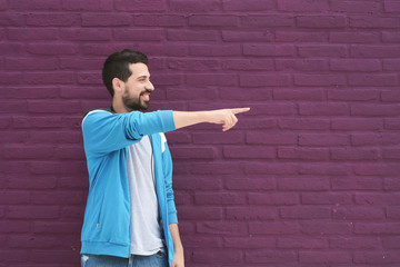 Portrait of young latin man pointing to space at right. Urban scene.