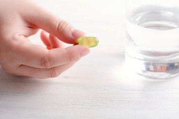 Female hand holding a pill.
