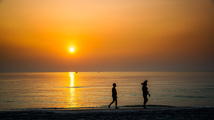 silhouette of couple walking by the sea at suns