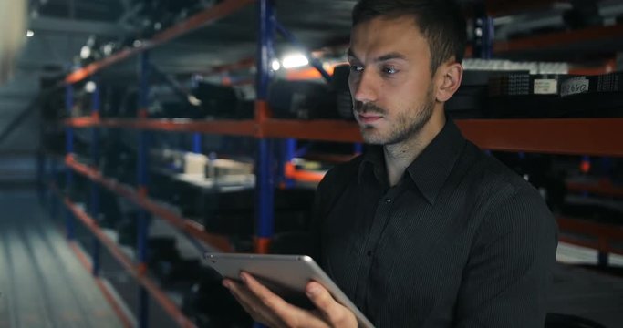 Serious strict warehouse manager using tablet pc in a large warehouse perspective