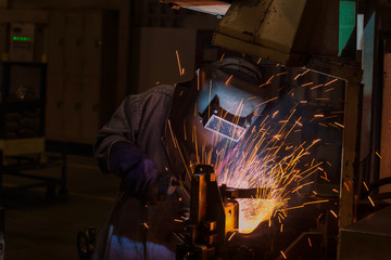 Fototapeta na wymiar Industrial worker with protective mask is welding metal .