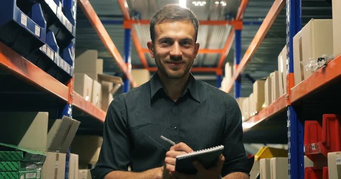 European warehouse worker with clipboard in strict dark-grey t-shirt on light background portrait
