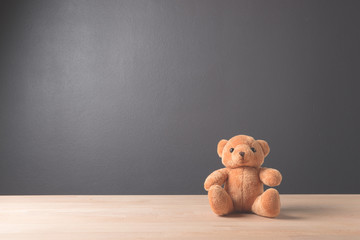 Teddy Bear toy alone on wood in front gray background