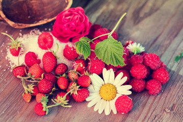 Composition from strawberries and raspberries on grunge wooden table