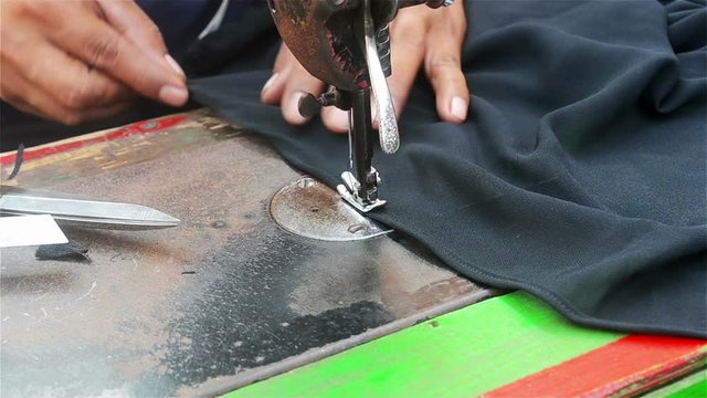 a tailor sewing black fabric / textile with sewing machine