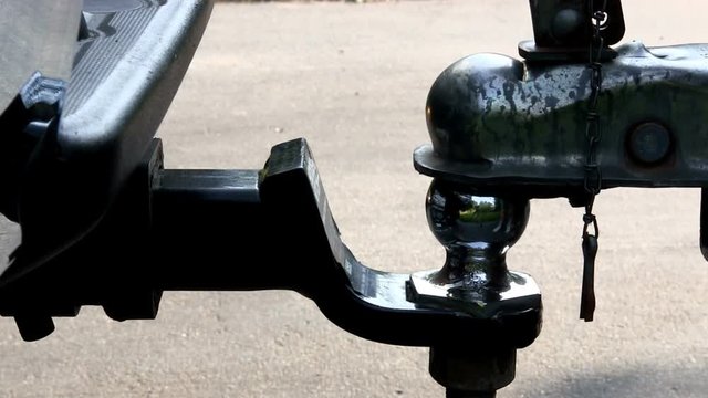 Boat trailer being lowered onto ball and hitch of truck, then latched and secured with cotter pin