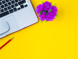 Flat lay, top view office table desk frame. feminine desk workspace with office accessories including calculator, mouse laptop, glasses, clips, red pencil, note book, blue pen  on yellow background.