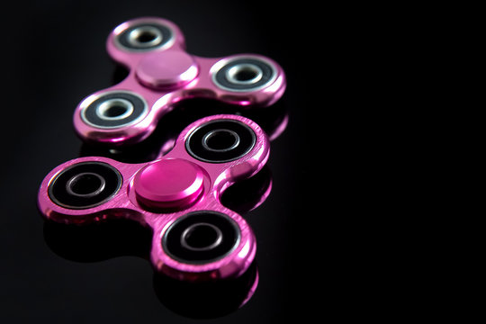 Fidget finger metal spinner, anxiety relief toy on black background, copyspace. Concept relieving stress