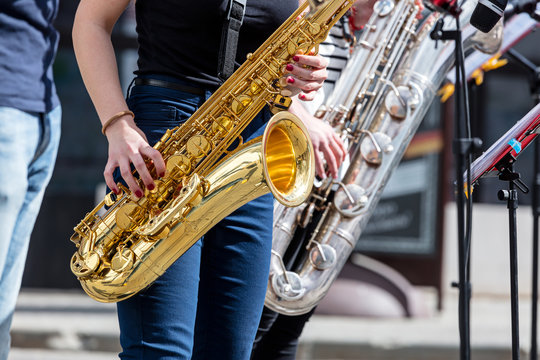 quartet of young saxophonists playing saxes during street performance