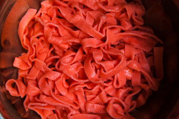 Colorful cooked tagliatelle closeup. Red fettuccine top view culinary background
