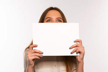 The girl is holding a sheet of blank paper in front of her
