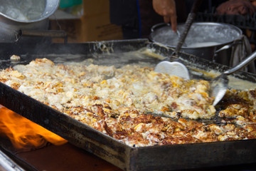  Cooking in thai food :Fried mussel pancakes or Oyster omelette (Hoi Tod) in local street food market. Traditional fried mussel stand in Thailand at street food vendor market