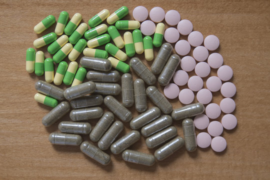 Drug pills in various shape and sizes on wooded table, space for text