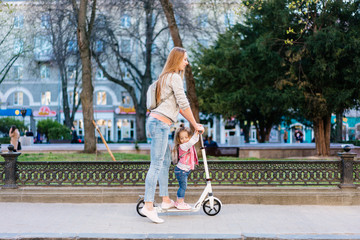 Fototapeta premium Mom and little daughter on a scooter