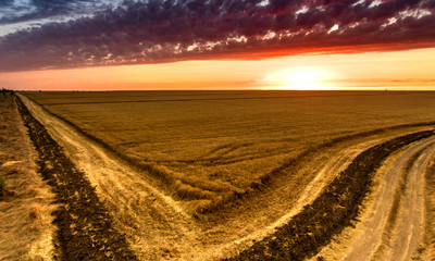 Fototapeta na wymiar Aerial shot of an agricultural and a crossroads at a bright orange sunset in Ukraine