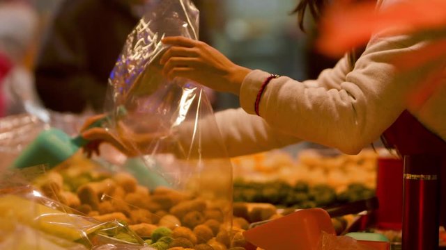 A saleswoman is preparing a bag to put the food. The Lunar New Year Fair in Dihua Street, a famous commercial place of Taipei, Taiwan.