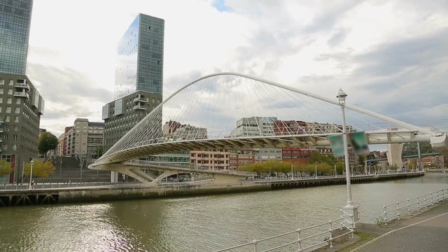 Footbridge connecting two banks of the river, viewed from bank against cityscape