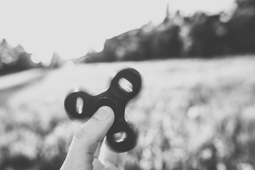 Fidget spinner in hand, summer background