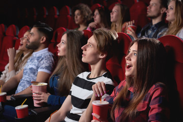 Group of people looking excited while watching a movie at the cinema audience lifestyle leisure...