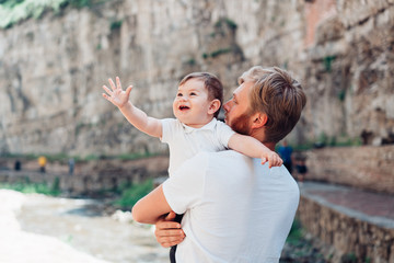 Dad and little son standing near a rock wall