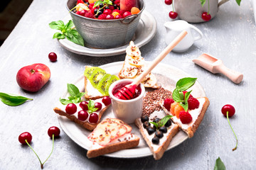Fruit toast on grey background. Healthy breakfast. Clean eating. Dieting concept. Grain bread slices with cream cheese and various fruit, berries, seeds. Vegetarian.