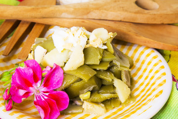 Bowl of green beans with egg on tablecloth with flowers